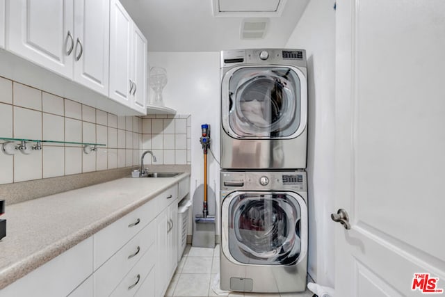 laundry area with sink, stacked washer and clothes dryer, light tile patterned floors, and cabinets