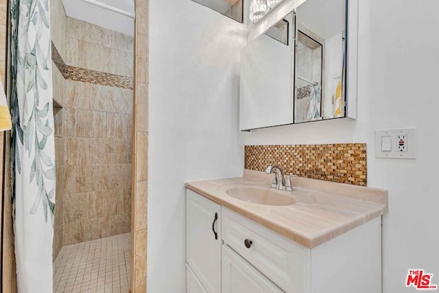 bathroom with vanity, tiled shower, and tasteful backsplash