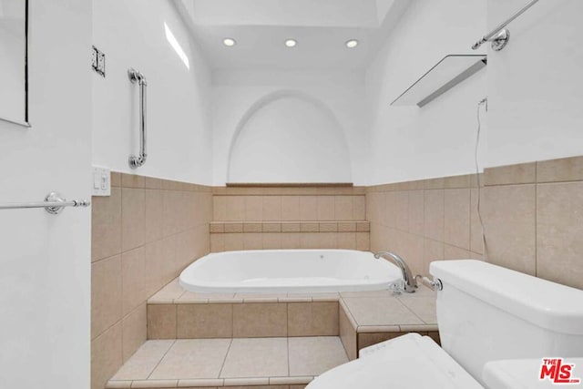 bathroom with toilet, tile walls, and tiled tub