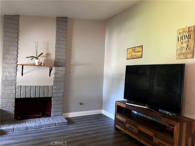 living room with a brick fireplace and dark hardwood / wood-style floors