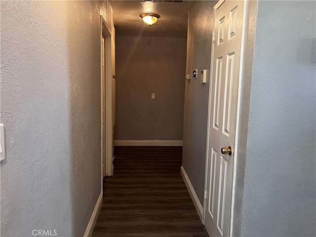 corridor featuring a textured ceiling and dark hardwood / wood-style flooring