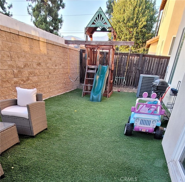 view of play area featuring a lawn and central AC unit