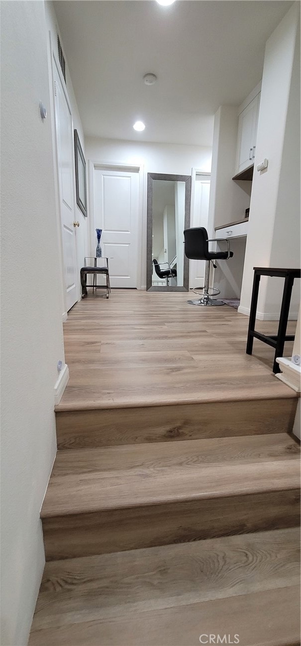 stairs featuring built in desk and hardwood / wood-style flooring