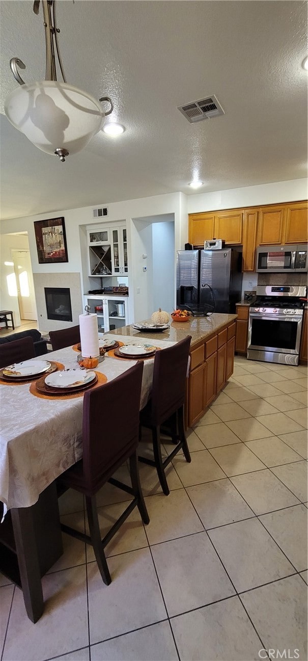 kitchen featuring stainless steel appliances, a textured ceiling, and light tile patterned floors