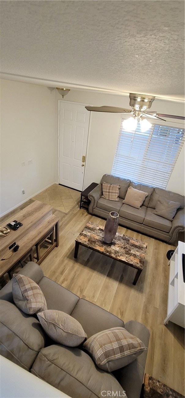 living room with hardwood / wood-style floors, a textured ceiling, and ceiling fan