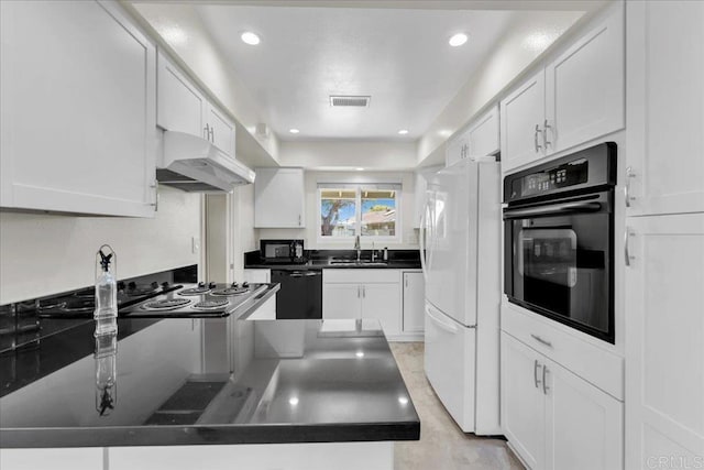 3685 Vista Campana N Unit 56, Oceanside, CA 92057 - kitchen with black appliances, under cabinet range hood, dark countertops, white cabinets, and recessed lighting