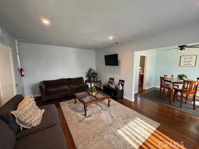 living room featuring ceiling fan and dark wood-type flooring