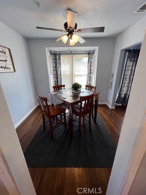 dining space featuring dark wood-type flooring, a textured ceiling, and ceiling fan