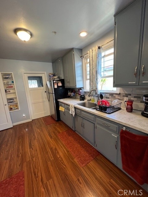 kitchen featuring dark wood-type flooring, backsplash, gray cabinets, and sink