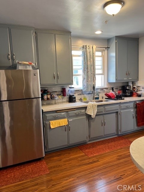 kitchen with dark hardwood / wood-style floors, gray cabinets, stainless steel fridge, and sink