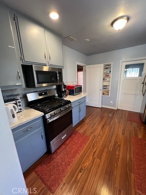 kitchen featuring appliances with stainless steel finishes, blue cabinets, white cabinetry, and dark hardwood / wood-style floors