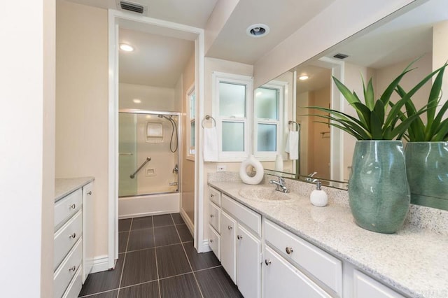 bathroom featuring tile patterned flooring, vanity, and bath / shower combo with glass door