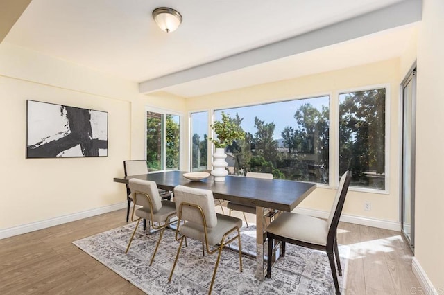 dining room featuring beam ceiling and light hardwood / wood-style flooring