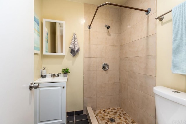 bathroom with vanity, toilet, and a tile shower