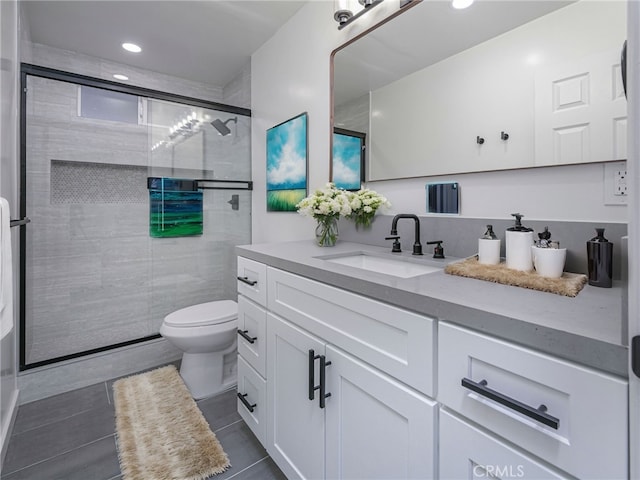 bathroom with toilet, a shower with shower door, vanity, and tile patterned floors