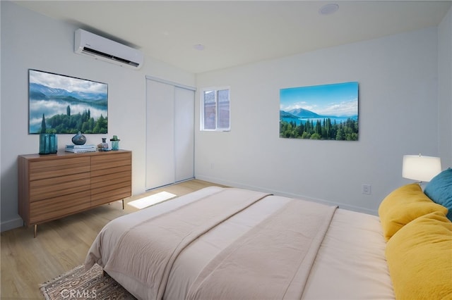 bedroom featuring a closet, a wall mounted AC, and light hardwood / wood-style flooring