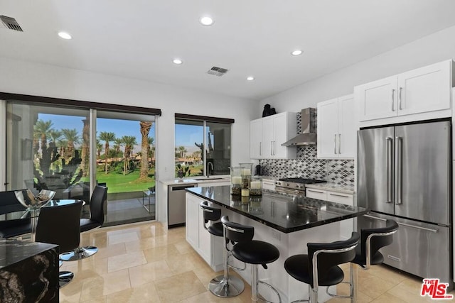 kitchen featuring white cabinetry, sink, a center island, wall chimney range hood, and high end appliances