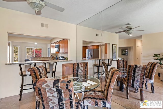 tiled dining area featuring ceiling fan and a textured ceiling