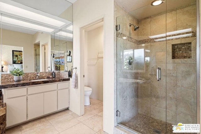 bathroom with tile patterned flooring, vanity, toilet, and walk in shower