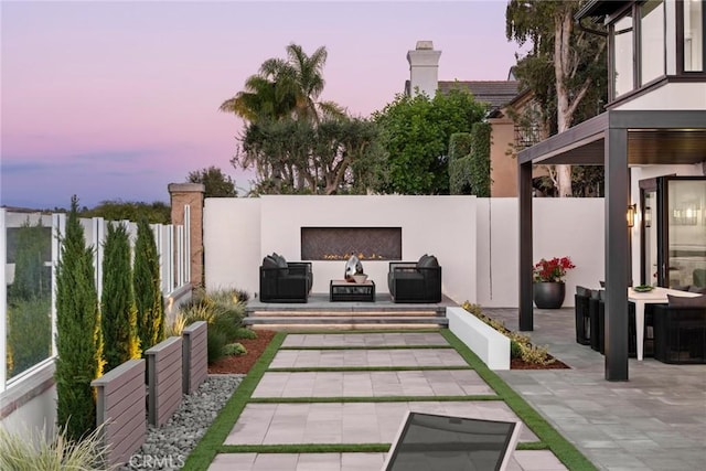 patio terrace at dusk featuring an outdoor fireplace