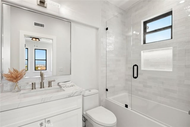 full bathroom featuring vanity, toilet, and bath / shower combo with glass door