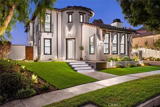 mediterranean / spanish home featuring a lawn and a balcony