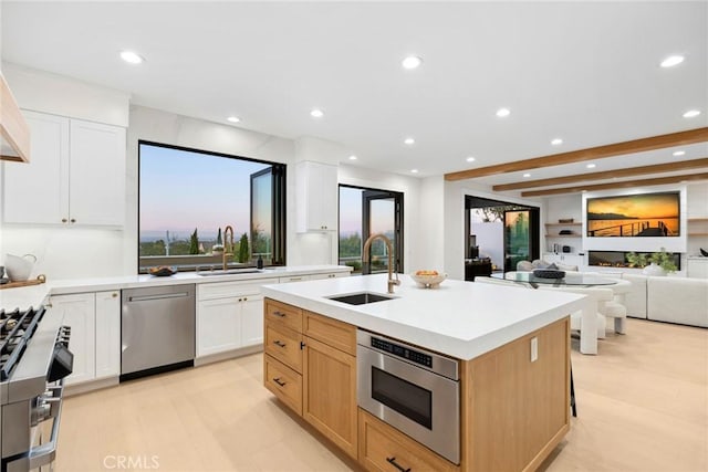 kitchen with white cabinets, sink, a center island with sink, and stainless steel appliances