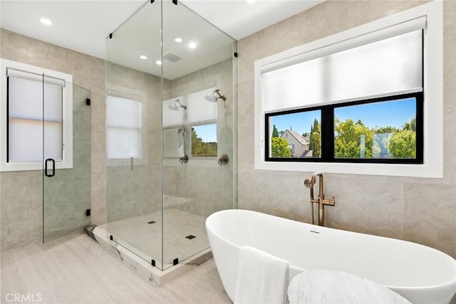 bathroom with tile walls and independent shower and bath