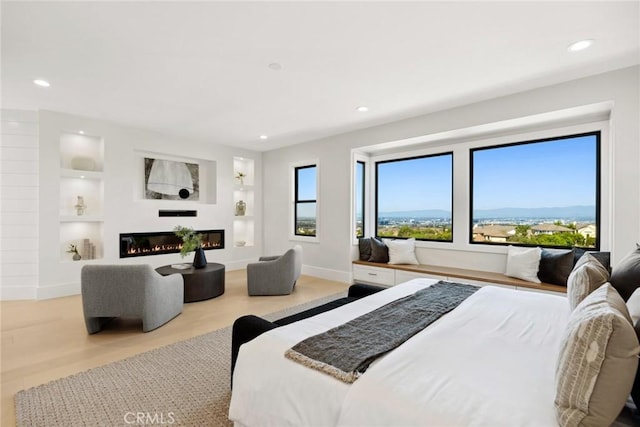 bedroom with a mountain view, light hardwood / wood-style floors, and multiple windows