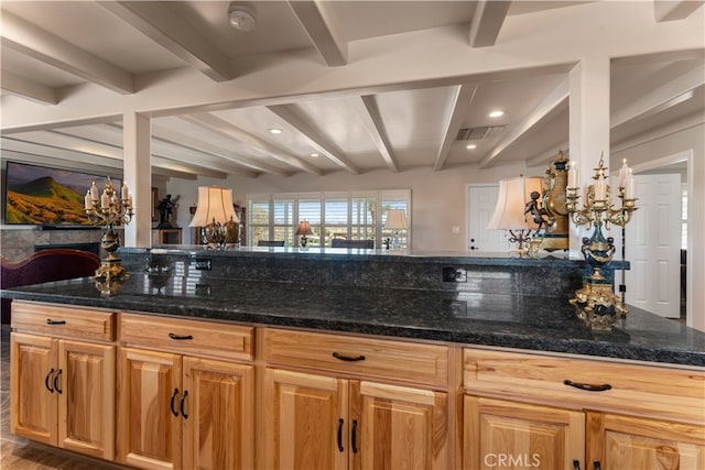 kitchen with dark stone counters and beam ceiling