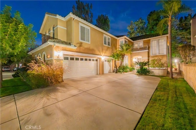 view of front of property with a garage, driveway, a balcony, and stucco siding