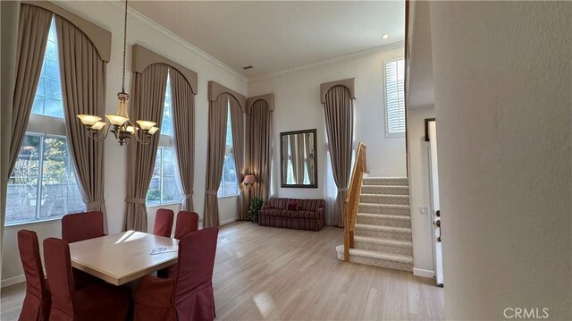 dining area featuring a wealth of natural light, crown molding, a notable chandelier, and light wood-type flooring