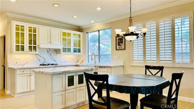 kitchen with white appliances, a kitchen island, white cabinetry, light wood-type flooring, and crown molding