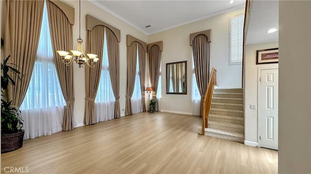 entryway featuring a notable chandelier, wood finished floors, crown molding, baseboards, and stairs