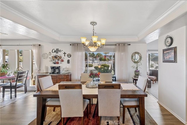 dining room featuring ornamental molding, a tray ceiling, dark wood-type flooring, and a notable chandelier