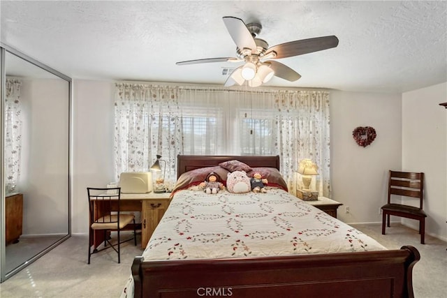 bedroom with ceiling fan, light colored carpet, and a textured ceiling