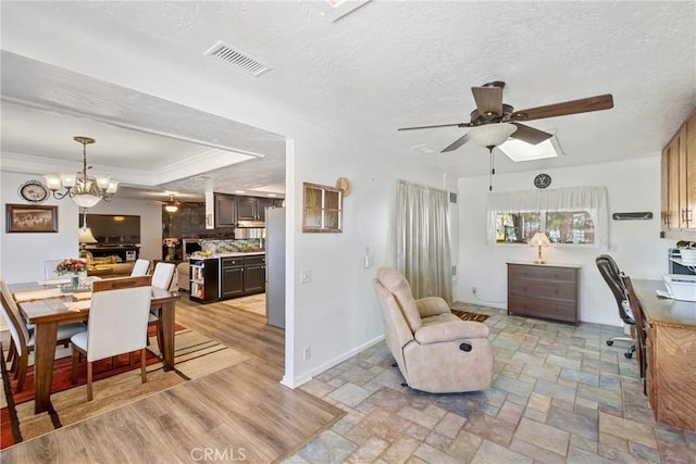 dining space featuring ceiling fan with notable chandelier, ornamental molding, a textured ceiling, and a tray ceiling