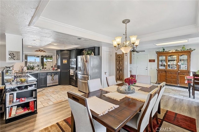 dining room with a textured ceiling, an inviting chandelier, light hardwood / wood-style flooring, and crown molding