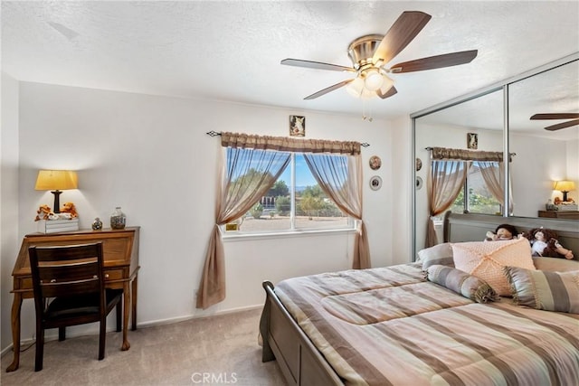 carpeted bedroom with ceiling fan, a closet, a textured ceiling, and multiple windows