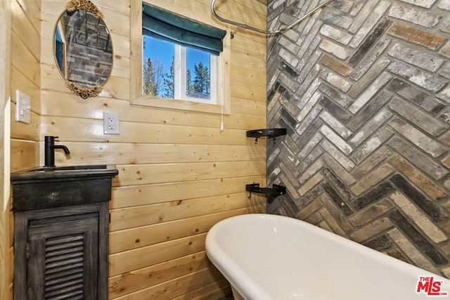 bathroom with vanity, a bathtub, and wooden walls