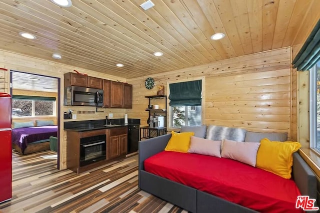 interior space featuring wood walls, hardwood / wood-style floors, wooden ceiling, and sink