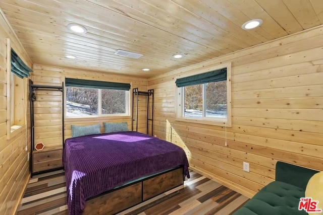 bedroom featuring wood-type flooring, wooden walls, and multiple windows