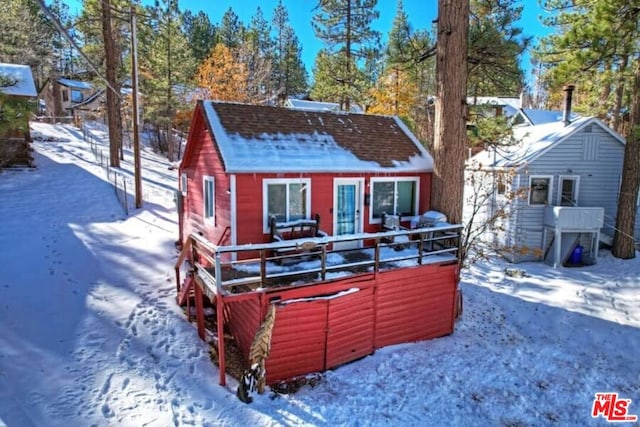 snow covered back of property with a wooden deck