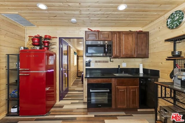 kitchen featuring wood walls, wooden ceiling, black appliances, sink, and light wood-type flooring