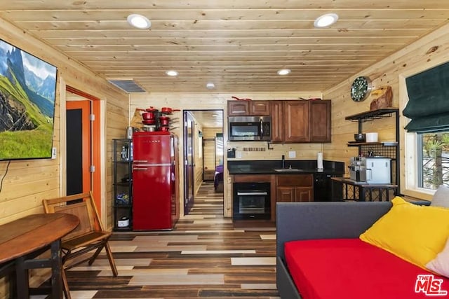 kitchen with dark hardwood / wood-style floors, oven, wood walls, and sink