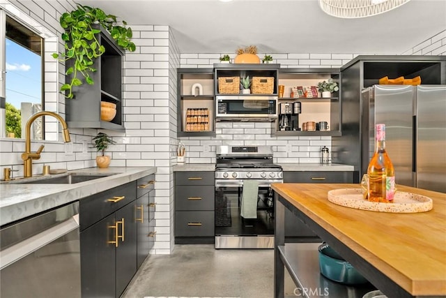 kitchen with wooden counters, backsplash, stainless steel appliances, and sink