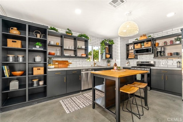 kitchen featuring decorative backsplash, sink, pendant lighting, and appliances with stainless steel finishes