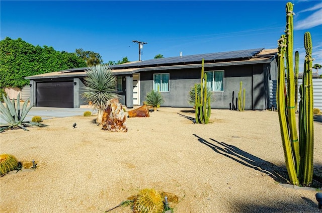 single story home featuring solar panels and a garage