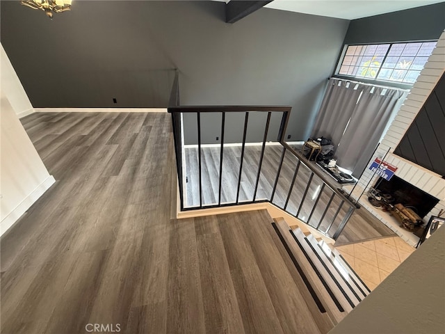 staircase featuring a brick fireplace and hardwood / wood-style flooring