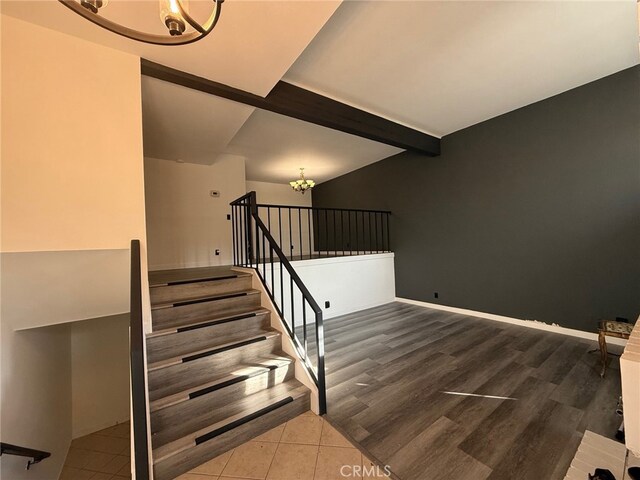 stairs featuring an inviting chandelier, hardwood / wood-style floors, and beamed ceiling